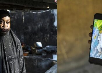 Guinean mother Mariam Soumah stands in her home in Conakry while holding a phone showing her premature baby daughter Sabina, who remains in a Belarus orphanage.