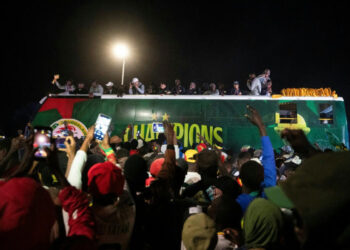 Senegal national football team celebrating atop an open-top bus as fans gather in Dakar following their Africa Cup of Nations victory.