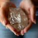 Hand holding a large rough diamond discovered in Botswana amid global market slowdown.
