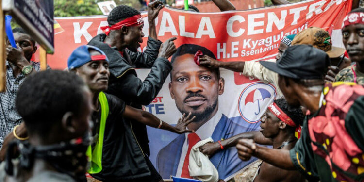 Supporters gather around a campaign banner of Ugandan opposition leader Bobi Wine during post-election unrest following President Museveni’s re-election