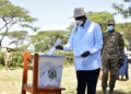 Uganda’s president casts his ballot at a polling station as security personnel stand nearby during the general election