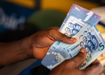 Hand holding Ghana cedi banknotes during a cash transaction