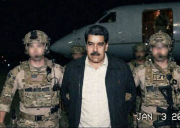 A detained male political figure escorted by masked US law enforcement officers on an airport tarmac at night, with a military aircraft in the background.