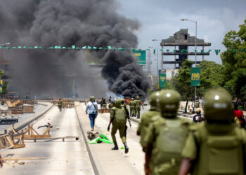 Tanzanian security forces advance during post-election unrest as smoke rises from burning barricades on a major road following the disputed October election.