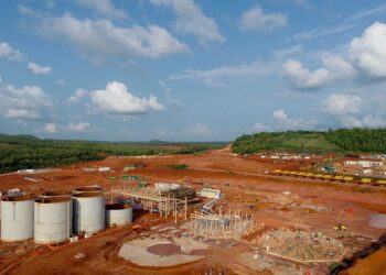 Aerial view of Ghana’s Ahafo gold mining project showing processing infrastructure, storage tanks and active construction amid red earth terrain.