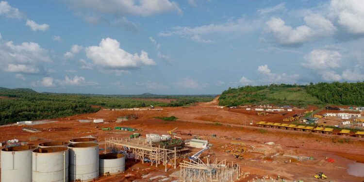 Aerial view of Ghana’s Ahafo gold mining project showing processing infrastructure, storage tanks and active construction amid red earth terrain.