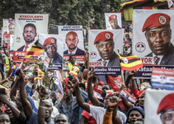Supporters hold campaign posters and Ugandan flags at an opposition rally in Kampala ahead of national elections, as authorities order an internet shutdown.