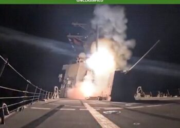 US naval vessel launches missile during overnight military strike operation, with flames and smoke visible from the deck