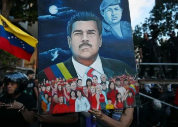 Illustrated portrait of Venezuela’s president held at a public gathering, with the Venezuelan flag visible and a crowd scene in the background