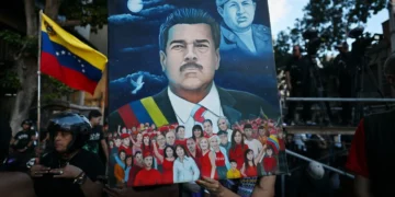 Illustrated portrait of Venezuela’s president held at a public gathering, with the Venezuelan flag visible and a crowd scene in the background