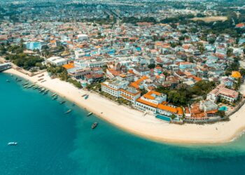 Aerial view of Zanzibar coastline showing Stone Town waterfront, beaches and hotels amid tourism growth