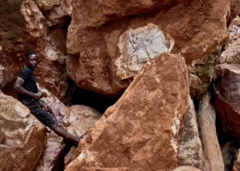 Artisanal miner standing among large rock formations at a mineral site in the Democratic Republic of the Congo, highlighting the country’s vast critical mineral reserves.