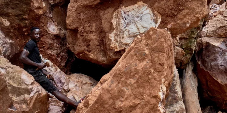 Artisanal miner standing among large rock formations at a mineral site in the Democratic Republic of the Congo, highlighting the country’s vast critical mineral reserves.