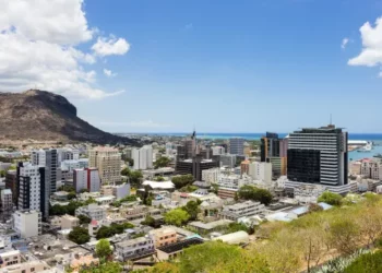 Aerial view of Port Louis, Mauritius, showing modern high-rise buildings, the harbour, and Le Pouce mountain under a clear blue sky