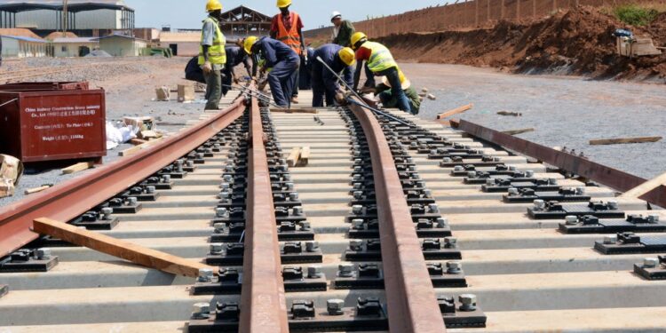 Construction workers installing railway tracks on a Standard Gauge Railway project in East Africa aimed at improving regional export transport links.