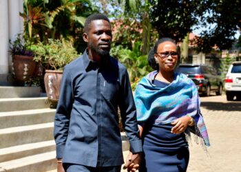 Bobi Wine walking outside with his wife Barbie Kyagulanyi, holding hands in Kampala, Uganda