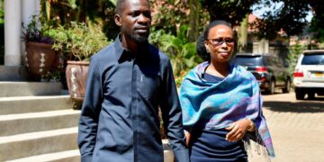 Bobi Wine walking outside with his wife Barbie Kyagulanyi, holding hands in Kampala, Uganda