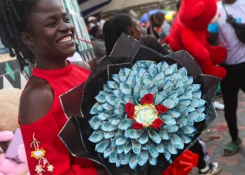Woman in Nairobi holding a Valentine’s bouquet made from folded Kenyan banknotes and red roses amid street celebrations