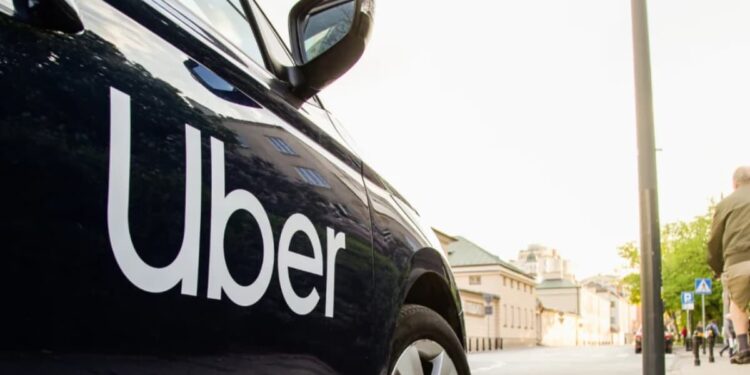 Close-up of a black Uber-branded car parked on a city street as pedestrians walk past, symbolising Uber’s exit from Tanzania