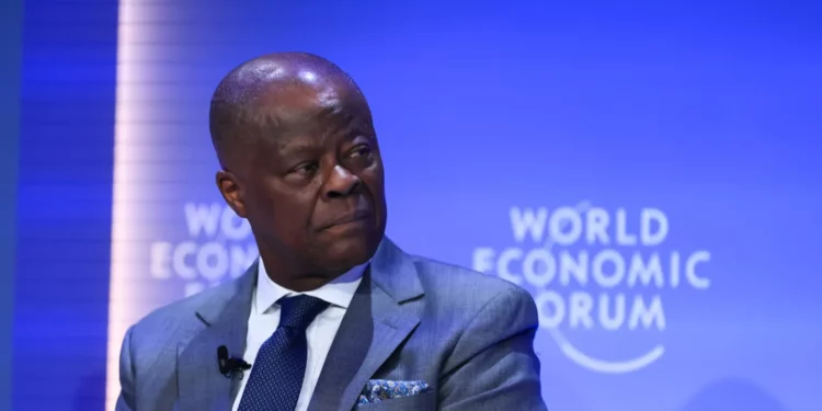 A senior Nigerian government official in a grey suit speaking during a panel session at the World Economic Forum, seated against a blue backdrop with the event logo visible