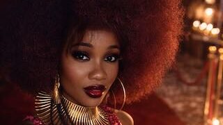 Woman with natural afro hairstyle wearing gold statement jewellery and red evening couture at a luxury fashion setting
