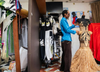 Gabonese fashion designer Chouchou Lazare adjusts a raffia dress in his Libreville studio, showcasing the traditional palm fibre used in his award-winning designs