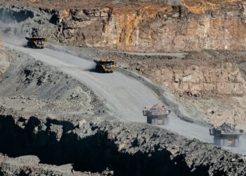 Open-pit mining trucks operating at a rare earth mineral site in Namibia, highlighting the scale of resource extraction for EV supply chains