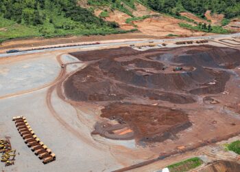 African iron-ore mining site with trucks and ore stockpiles near railway infrastructure