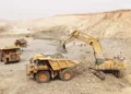 Open-pit mining trucks and excavator operating at a gold mine in Senegal amid government review of mining licences.