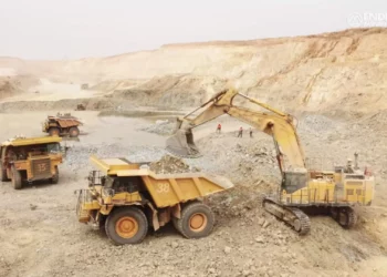 Open-pit mining trucks and excavator operating at a gold mine in Senegal amid government review of mining licences.