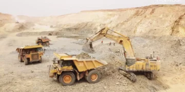 Open-pit mining trucks and excavator operating at a gold mine in Senegal amid government review of mining licences.