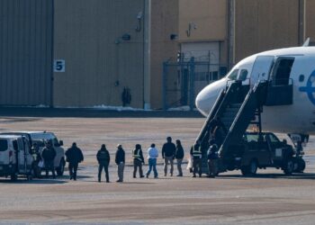 Migrants escorted by officers board a deportation flight in the United States during immigration enforcement operations under President Donald Trump’s deportation policy