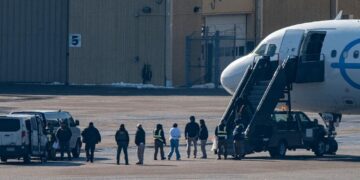 Migrants escorted by officers board a deportation flight in the United States during immigration enforcement operations under President Donald Trump’s deportation policy
