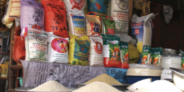 Rice sacks and measured grains displayed at a market stall in The Gambia, illustrating the country’s high rice consumption and dependence on staple imports