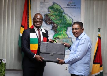 Zimbabwe envoy Amon Murwira and Guyana agriculture minister exchange documents during bilateral talks on agriculture cooperation in Georgetown