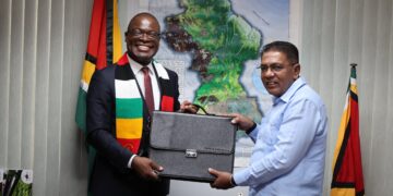 Zimbabwe envoy Amon Murwira and Guyana agriculture minister exchange documents during bilateral talks on agriculture cooperation in Georgetown