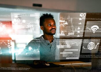 Man analysing multiple digital data dashboards and algorithms on transparent screens, illustrating how metrics and data systems shape human decision-making