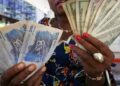 Woman holding US dollar and Congolese franc banknotes in DR Congo, illustrating dollarisation and cash transactions