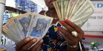 Woman holding US dollar and Congolese franc banknotes in DR Congo, illustrating dollarisation and cash transactions