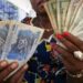 Woman holding US dollar and Congolese franc banknotes in DR Congo, illustrating dollarisation and cash transactions