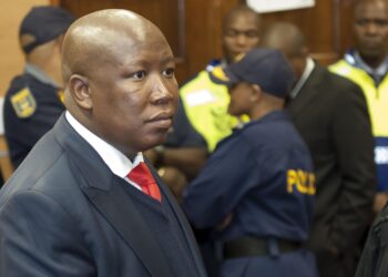 Julius Malema in court during sentencing in South Africa as police stand behind him