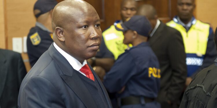 Julius Malema in court during sentencing in South Africa as police stand behind him