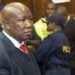 Julius Malema in court during sentencing in South Africa as police stand behind him