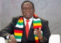 Zimbabwe President Emmerson Mnangagwa speaking at a public event, wearing a national flag scarf and suit