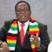Zimbabwe President Emmerson Mnangagwa speaking at a public event, wearing a national flag scarf and suit