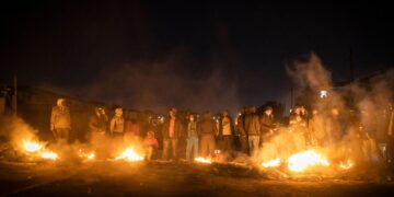 Protesters gather around burning barricades during night unrest in a South African township