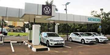 Electric vehicles charging at a public EV station in Kigali, Rwanda, featuring Volkswagen cars under a Siemens-branded charging canopy