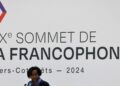 Louise Mushikiwabo speaks beneath a large Francophonie Summit sign during the 2024 summit in Villers-Cotterêts, France