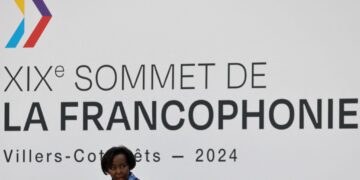 Louise Mushikiwabo speaks beneath a large Francophonie Summit sign during the 2024 summit in Villers-Cotterêts, France