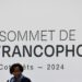 Louise Mushikiwabo speaks beneath a large Francophonie Summit sign during the 2024 summit in Villers-Cotterêts, France